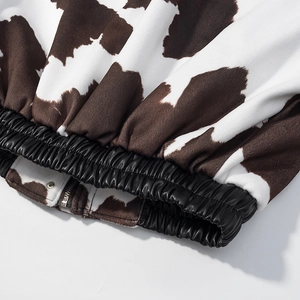 Detailed close-up of cow print fleece and black PU leather elastic hem on a street jacket