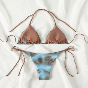 Tie-dye bikini set with halter top and side-tie bottoms in blue and brown on linen background