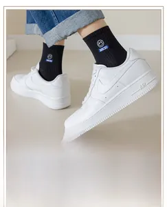 Close-up of black crew sock featuring white smiley face embroidery and NICE text