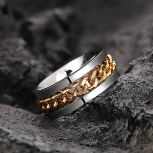 Macro shot of silver stainless steel spinner ring with rotating gold Cuban chain detail