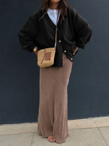 Detail of a black V-neck knit cardigan paired with a woven shoulder bag and brown skirt