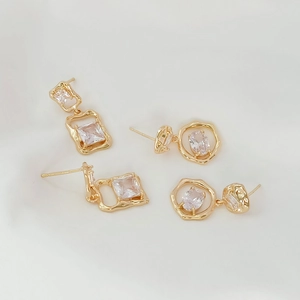 Detailed macro of 14K gold plated earrings with clear zircon stones on silk fabric