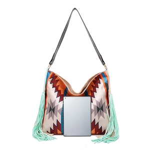 Detail of bohemian tote bag with fringe and ethnic patterns next to a tablet for size