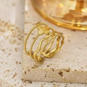 Detailed close-up of an 18k gold-plated clover ring on a textured stone surface