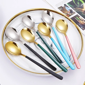 Detail of colorful matte handle spoons with gold and silver mirror finish heads on a marble plate