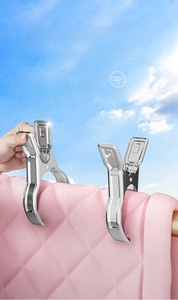 Detail of heavy duty stainless steel clothespins gripping a thick pink quilt outdoor