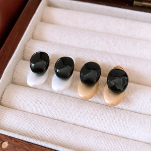 Detail of silver and gold geometric earrings with black resin inlay in a jewelry box