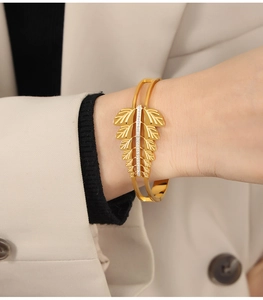 Macro detail of gold-plated leaf bangle featuring embossed veins and micro-set crystals