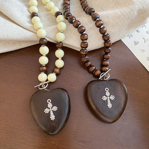 Détail de colliers avec pendentifs en cœur de bois et croix en métal argenté