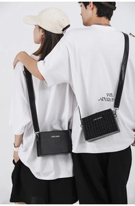 Detail of couple wearing black box bags in smooth and crocodile embossed textures