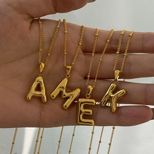 Golden 3D balloon initial pendant necklace with bead chain shown in hand