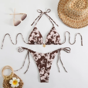 Flat lay of tropical floral bikini set with gold petal charms and beach accessories