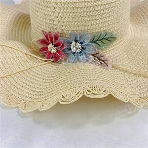 Beige straw sun hat with wavy brim and rhinestone floral embroidery for beach vacation