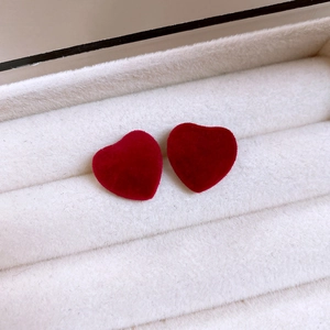 Close-up of deep red velvet heart earrings displayed in a beige jewelry box