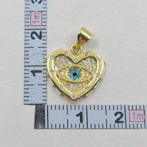 Gold heart evil eye pendant with blue zircon stones measured with a ruler for size