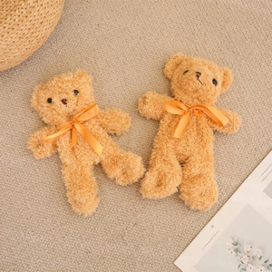 Two small brown teddy bears with curly fleece and orange bows on a cozy background