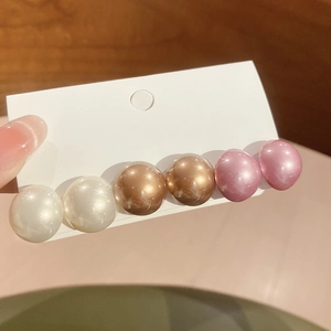 Detail of round pearl and cat-eye stone hair clip with white, amber, and pink beads