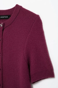 Detail of burgundy knit cardigan featuring decorative silver bow buttons and plush texture