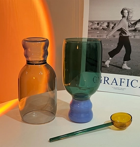 Artistic detail of amber and green borosilicate glass cups with vibrant blue base accents