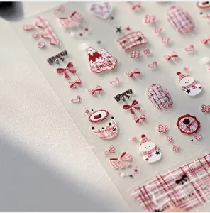Close-up of matte nail stickers with red plaid, heart, and snowman designs for winter