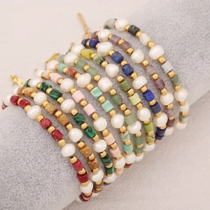Bohemian natural stone and pearl bracelets set with gold beads on a display stand