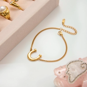 Detail of a gold horseshoe pendant bracelet with lobster clasp and adjustable chain link