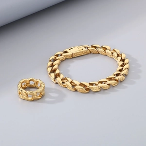 Detail of gold Cuban chain bracelet and ring set with intricate engraved metal texture