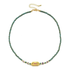 Close-up of turquoise beaded necklace featuring a gold evil eye pendant and extender chain