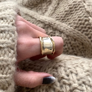 Close-up of a wide polished gold minimalist geometric ring worn on a finger