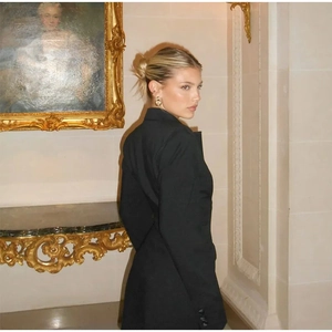 Détail d'une robe blazer noire à col en V montrant la coupe ajustée et les boutons de manche