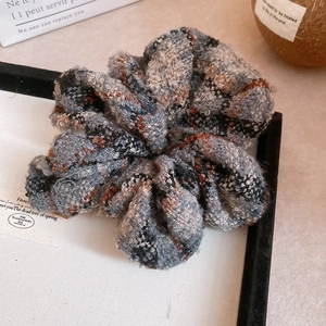 Gros plan d'un chouchou en tweed à carreaux orange et noir pour coiffures rétro