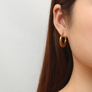 Fashion twisted irregular stainless steel hoop earrings in gold on female model