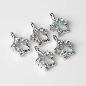 Macro detail of silver star pendants with aurora blue glitter and crystal rhinestones