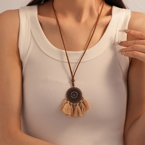 Detail of vintage bronze mandala pendant with light camel silk tassel on a long necklace