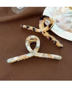 Macro view of large acetate claw clips in tortoiseshell and marble patterns on a tray