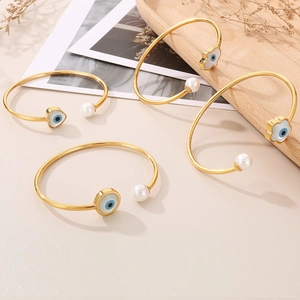 Détail de quatre bracelets dorés œil protecteur avec perles sur fond minimaliste