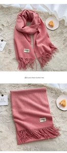 Detailed close-up of pink cashmere-feel scarf with elegant fringes and branded woven label