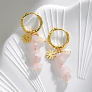 Detail of 14k gold earrings featuring pink natural stones, white pearls and daisy charms