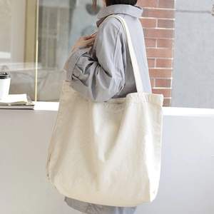 Minimalist off-white canvas tote bag with large capacity shown in casual street style