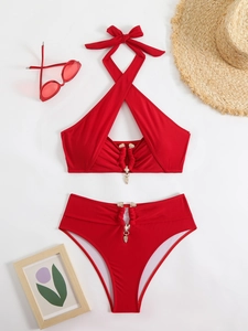 Flat lay of red bikini with gold hardware, sun hat and sunglasses on white background