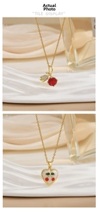 Close-up of gold cherry pendant with red crystal and heart enamel pendant detail