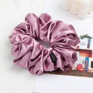 Detail shot of a large pink satin scrunchie featuring a premium GoodMood woven label