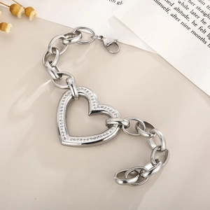 Macro detail of silver link chain bracelet featuring a sparkling rhinestone heart pendant