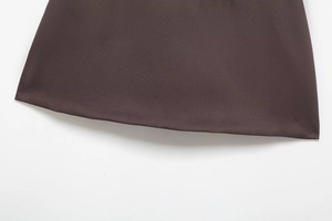 Macro detail of dark brown plain weave fabric hem on elegant skirt shorts with belt