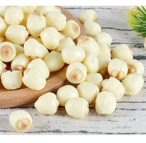 Close-up of PVC artificial white lotus seeds on a wooden plate and striped cloth