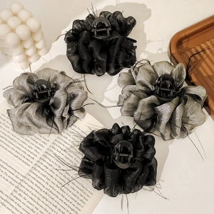 Close-up of elegant black and grey organza flower hair clips on a wooden tray