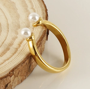 Détail d'une bague ouverte en acier doré 18 carats avec deux perles blanches