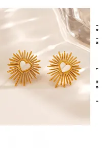 Dettaglio degli orecchini a cuore dorati con motivo a raggiera e design traforato