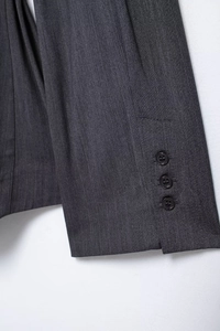 Detailed close-up of dark grey pinstripe suit cuffs featuring three black buttons