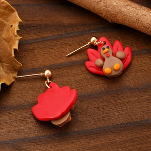 Detail of handmade polymer clay turkey earrings featuring festive autumn maple leaf theme